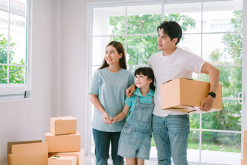 Fototapeta na wymiar Young happy asian family carring cardboard box moving into new home, Father mother and daughter moving to new house, New property and relocation concept.