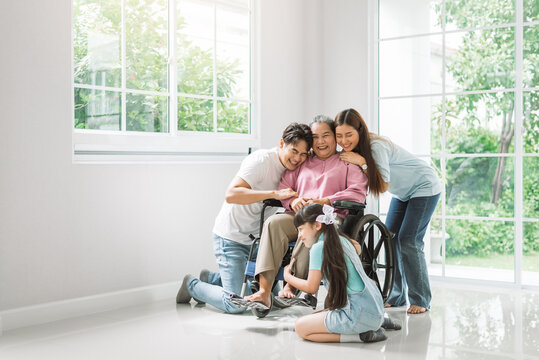 Happy Asian Family Spending Time Together At New Home, Grandmother On Wheelchair With Family Members.