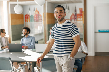 Portrait of smiling businessman in casual clothes standing in modern office 