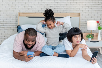 A 5-year-old African-American girl, showing up in a bad mood because her parents are not interested, and using mobile phones all the time, to family and social media concept.