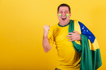 adult man, soccer fan from brazil, wearing flag, celebrating soccer match.