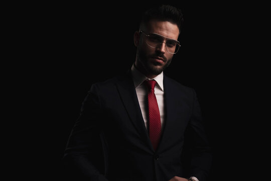 unshaved young guy in elegant black suit with red tie and eyeglasses