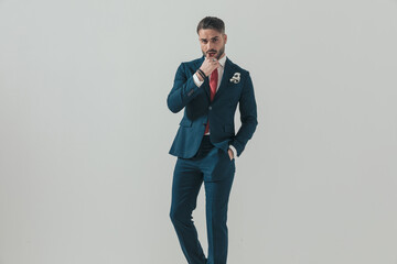 sexy young businessman with hand in pocket touching lips
