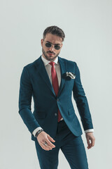 cool stylish businessman in suit with retro sunglasses posing