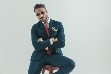 confident young man in suit with retro sunglasses crossing arms