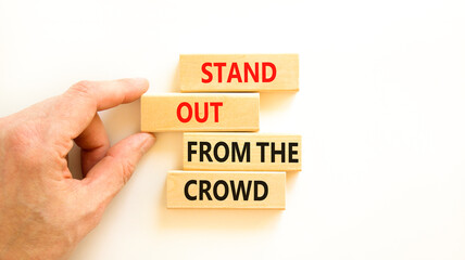 Stand out from the crowd symbol. Concept words Stand out from the crowd on wooden blocks on beautiful white table white background. Businessman hand. Business, stand out from the crowd concept
