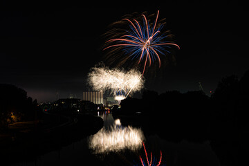 Fireworks above the river canal Roeselare-leie.  Reflections in water of fireworks in flanders Izegem.  Commercial firework photos from in Belgium