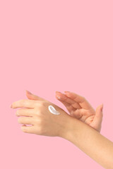 Female hands on a pink background smear cream, long beige nails, manicure and gel polish. Woman...