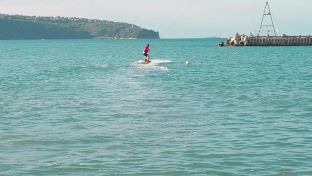 Training for surfers and windsurfers on the water. Back view wake surfer rides board on a wakepark
