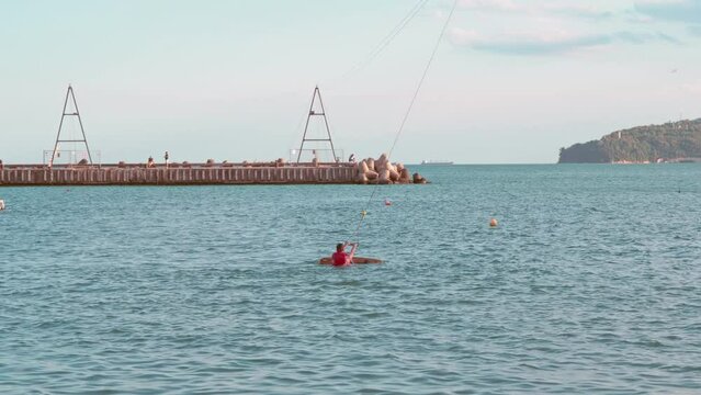wakepark with beginner wakeboarder wears life jacket and surf on sea weaves