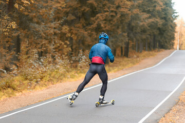 Fototapeta premium Cross country skilling.A man on roller skis rides in the autumn park.