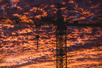 Naklejka premium Construction crane in the middle of a burning sky