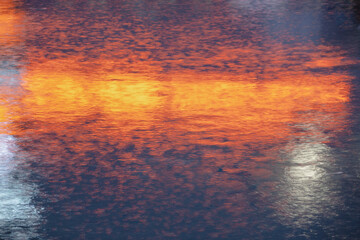 reflection from advertising lights in heavy rain on asphalt in the evening