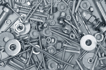 Set of different nuts, bolts, screws, washers and drill bits, on steel plate background.