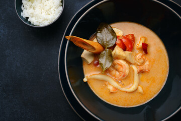 Thai soup with seafood and rice, on dark concrete