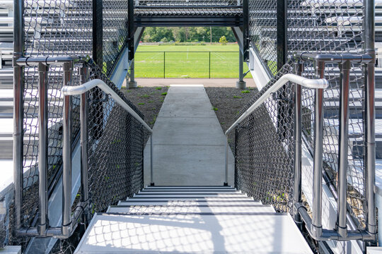 Example of an exit, entrance, vomitorium at empty set of metal stadium bleacher - grandstands with steps and railing.  Nondescript location with no people in image.  Not a ticketed event.    	