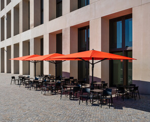 empty cafe house tables and red umbrellas of a restaurant 