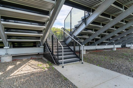 Example of an exit, entrance, vomitorium at empty set of metal stadium bleacher - grandstands with steps and railing.  Nondescript location with no people in image.  Not a ticketed event.    	