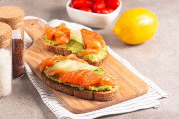 Two tasty open salmon sandwiches with avocado and cucumber. Morning healthy breakfast. Top view.