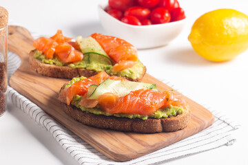 Two tasty open salmon sandwiches with avocado and cucumber. Morning healthy breakfast. Top view.
