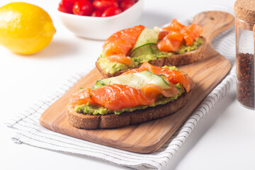 Two tasty open salmon sandwiches with avocado and cucumber. Morning healthy breakfast. Top view.
