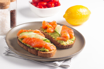 Two tasty open salmon sandwiches with avocado and cucumber. Morning healthy breakfast. Top view.