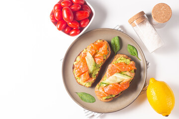 Two tasty open salmon sandwiches with avocado and cucumber. Morning healthy breakfast. Top view.
