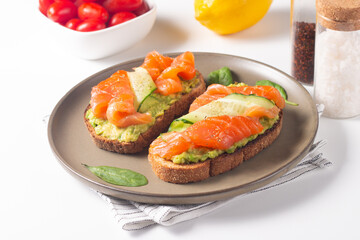 Two tasty open salmon sandwiches with avocado and cucumber. Morning healthy breakfast. Top view.