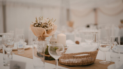 Event and catering agency organization modern wedding. Table for guests assembled with dishes, cutlery, glasses and flowers, candles and elements.