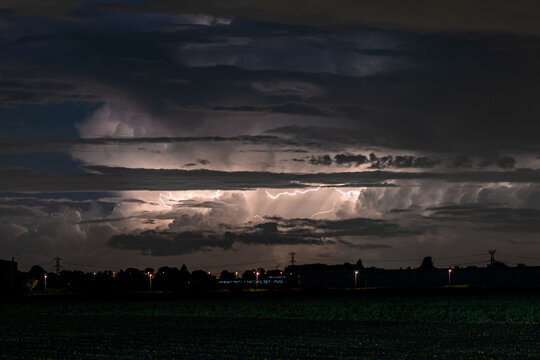 A Cumulonimbus storm cloud is lit up by lightning at night