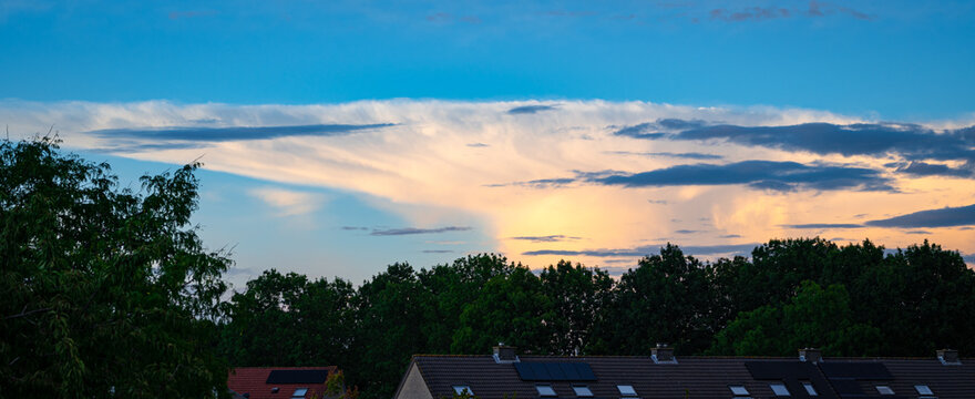 Large anvil of a distant storm cloud is illuminated by the low sun