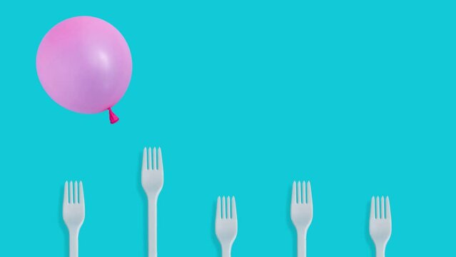 Creative concept with pink balloon flying over kitchen forks on pastel blue background 4k.