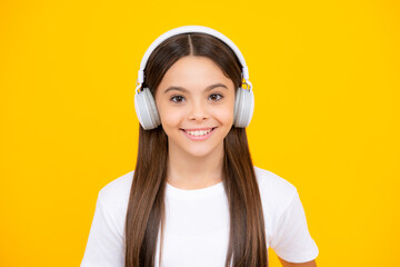 Teenager child girl in headphones listening music, wearing stylish casual outfit isolated over yellow background. Happy teenager portrait. Smiling girl.