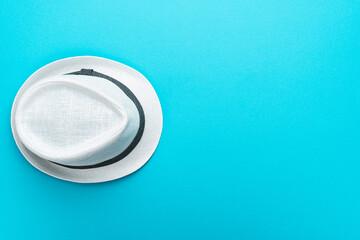 Top view of trilby over turquoise blue background. Flat lay top-down composition of white trilby...