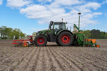 Grüner Traktor mit landwirtschaftlichen Geräte beim Maislegenauf einen Feld.