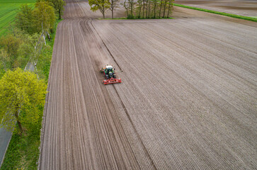 Drohnenfoto - Maislegen mit Trecker und Maschinen auf einen trockenen Ackerboden.