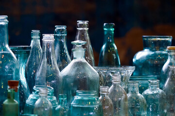 Set of decorative glass bottles and vases of different sizes on dark background. Old glass bottles collection
