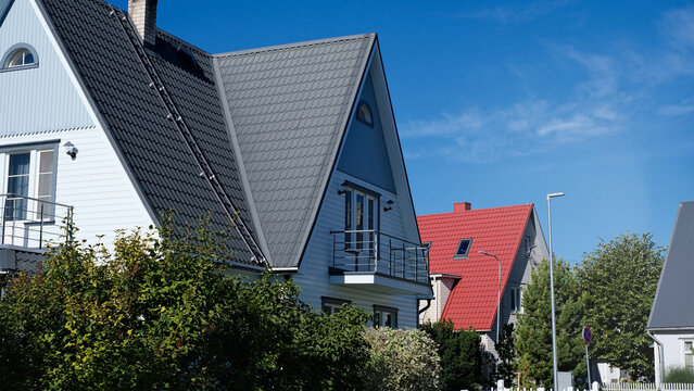 A private house of two floors with triangular roof and an area near the house against a blue sky