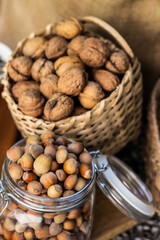 Walnuts and Hazelnuts in a wicker basket on old wooden table