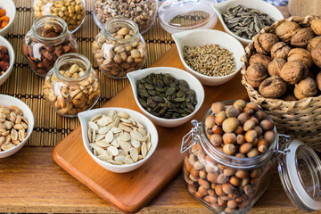 Rustic wood table filled with a large assortment of nuts like pistachios, hazelnut, pine nut, almonds, pumpkin seeds, sunflower seeds, peanuts, cashew and walnuts