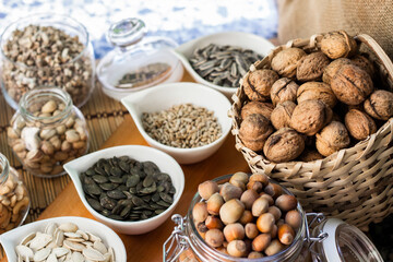 Rustic wood table filled with a large assortment of nuts like pistachios, hazelnut, pine nut, almonds, pumpkin seeds, sunflower seeds, peanuts, cashew and walnuts