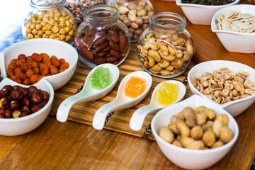Rustic wood table filled with a large assortment of nuts like pistachios, hazelnut, pine nut, almonds, pumpkin seeds, sunflower seeds, peanuts, cashew and walnuts