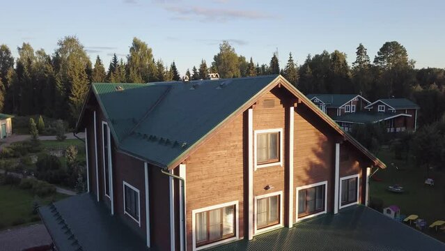 wooden country house in a cottage village on a summer recreation center among green trees. guest house in the rays of the sun. Hunting lodge shooting from a height from a drone.