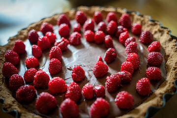Delicious full chocolate tart with several raspberry on top, close up of fruit cake dessert , selective focus