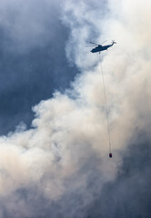 Wildfire Service Helicopter flying over BC Forest Fire and Smoke on the mountain near Hope during a hot sunny summer day. British Columbia, Canada. Natural Disaster
