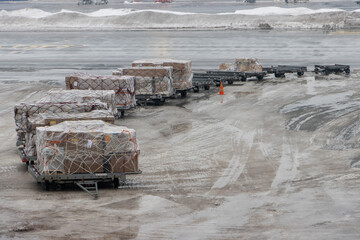 Carts loaded with paper boxes stand at a snowy airport