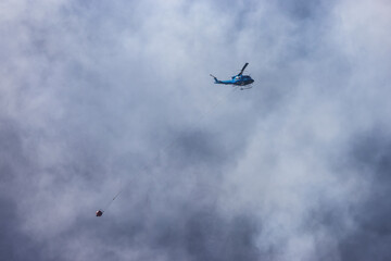 Wildfire Service Helicopter flying over BC Forest Fire and Smoke on the mountain near Hope during a hot sunny summer day. British Columbia, Canada. Natural Disaster