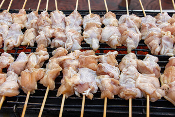 Raw meat on a stick is grilled on the grill. Preparing chicken on a stick in a Thai market