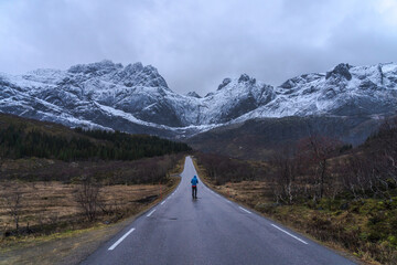 Unrecognizable traveler on road against mountains