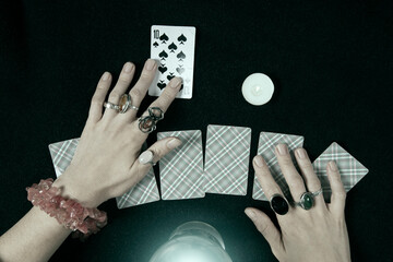 Fortune teller or witch hands, cards, candles and a glowing magic ball. Halloween, magic and tricks concept.